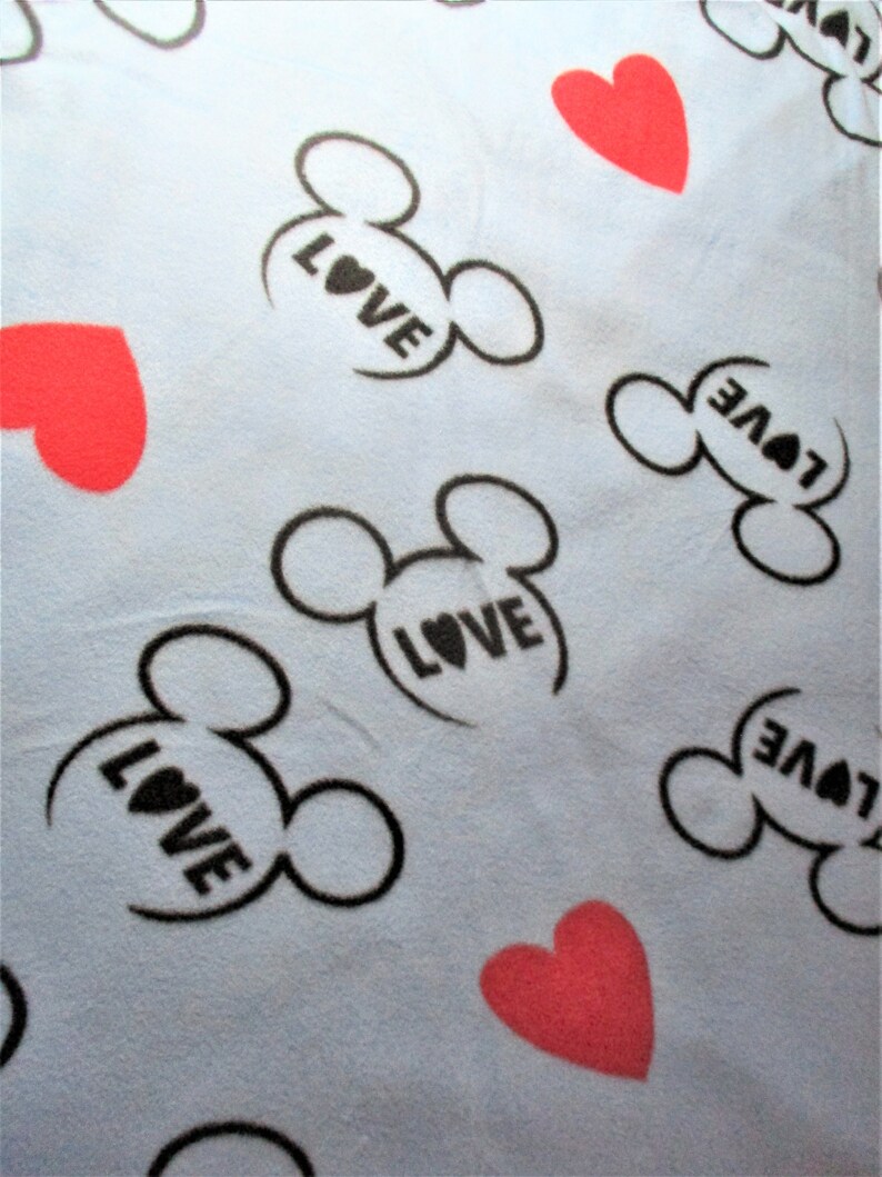May include: A light blue fabric with a repeating pattern of black Mickey Mouse ears with the word "LOVE" inside each ear and red hearts.