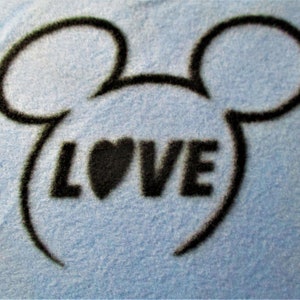 May include: A blue fabric background with a black outline of Mickey Mouse ears and the word "LOVE" in black with a black heart in the middle of the word.