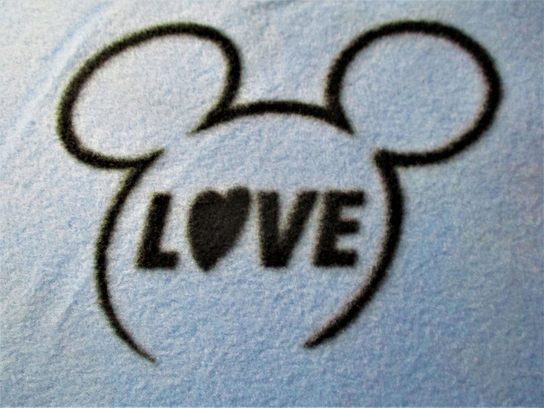 May include: A blue fabric background with a black outline of Mickey Mouse ears and the word "LOVE" in black with a black heart in the middle of the word.