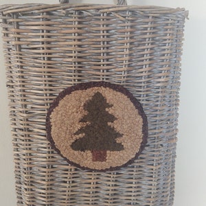 May include: A gray wicker wall basket with a brown, tan, and green woven tree design.
