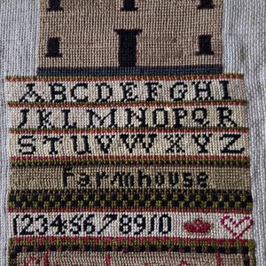 May include: A framed needlepoint sampler featuring a house, alphabet, numbers, and the words "Farmhouse" and "Glory be to God." The year "1834" is stitched above the house. The sampler uses a variety of colors, including tan, black, red, and green.