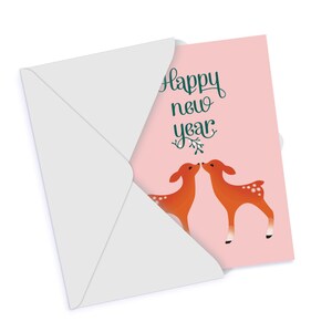 May include: A pink card with the text "Happy New Year" in green script. Two orange deer are kissing on the card.