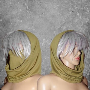 Peut inclure: Deux mannequins portant des &eacute;charpes &agrave; capuche vert olive. Les &eacute;charpes sont drap&eacute;es autour du cou et du visage, avec la capuche relev&eacute;e. Les mannequins ont la peau p&acirc;le et des perruques grises. Le fond est un mur gris textur&eacute;.
