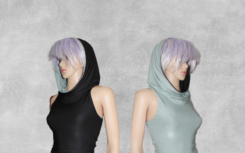 May include: Two sleeveless tops with a cowl neck and a hood. The top on the left is black with a light blue hood lining. The top on the right is light blue with a black hood lining.