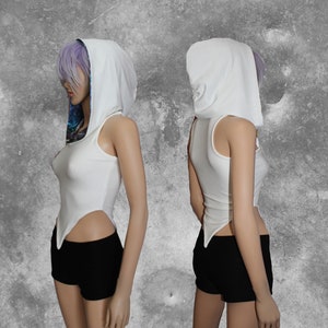 May include: White sleeveless crop top with a white hooded neckline. The top has a long, pointed hem on each side. The model is wearing black shorts.