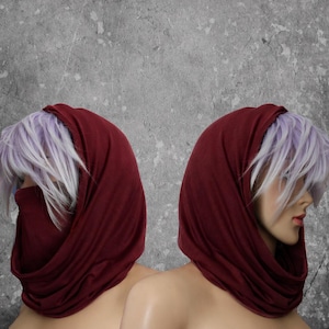 Peut inclure: Deux mannequins avec des couvre-chefs bordeaux et des cheveux violets clairs et blancs. Les couvre-chefs sont drap&eacute;s autour du cou et du visage. Le fond est gris mouchet&eacute;.