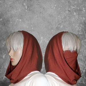 Peut inclure: Deux mannequins portent des capuches de couleur rouille. Les capuches sont faites d'un tissu doux et couvrent la t&ecirc;te et le cou, avec la possibilit&eacute; de couvrir le bas du visage. Les mannequins ont la peau p&acirc;le et les cheveux courts et clairs. Le fond est un mur gris textur&eacute;.