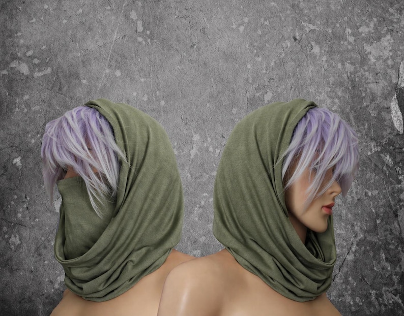 Peut inclure: Deux mannequins avec des perruques lavande et des couvre-chefs vert olive. Le tissu est drap&eacute; autour du cou et du visage. Le fond est gris mouchet&eacute;.