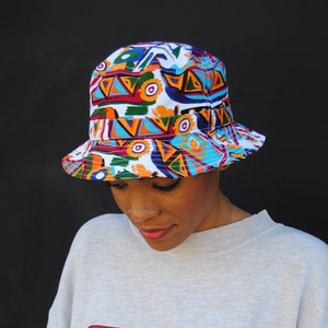 Model wearing vintage FILA sweatshirt and white bucket hat with colorful 90s abstract design.