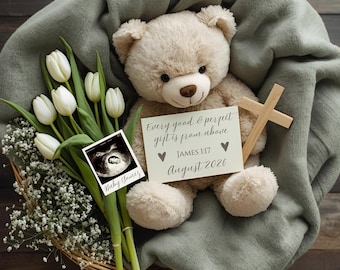 May include: A beige teddy bear rests on a green blanket, holding a wooden cross and a card with text. A bouquet of white tulips and baby's breath sits in a woven basket, with a sonogram photo. The card reads "Every good & perfect gift is from above."
