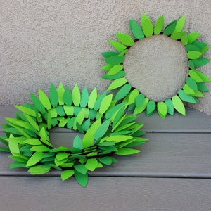 May include: Two green paper leaf wreaths, one is a circle and the other is a continuous loop.