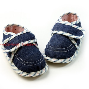 K&ouml;nnte beinhalten: Ein Paar blaue Baby-Schuhe aus Denim mit wei&szlig;em und rosafarbenem Karomuster und Klettverschluss.