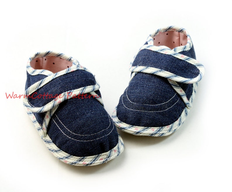 K&ouml;nnte beinhalten: Ein Paar blaue Baby-Schuhe aus Denim mit wei&szlig;em und rosafarbenem Karomuster und Klettverschluss.