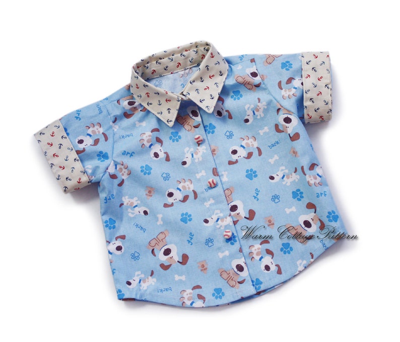 May include: A light blue short-sleeved shirt with a white collar and cuffs. The shirt has a pattern of brown dogs with the words "arf", "bark", and "back!" on it.