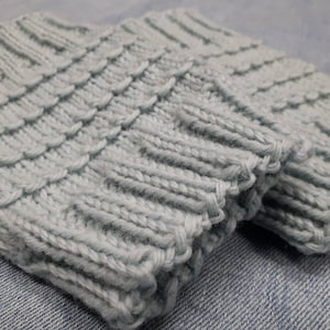 May include: A pair of light blue knitted boot cuffs. The cuffs are made from a soft, textured yarn and have a simple, classic design.
