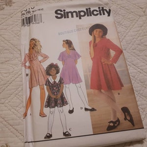 Könnte beinhalten: Simplicity-Schnittmuster für Mädchenkleider. Das Schnittmuster enthält drei verschiedene Stile: ein Kleid mit Rüschenkragen, ein Kleid mit Peter-Pan-Kragen und ein Kleid mit Schleife am Ausschnitt. Das Schnittmuster ist für die Größen 8-16.