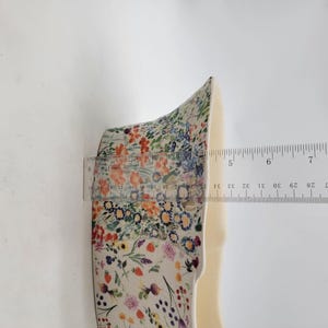 Puede incluir: Objeto con estampado floral con una regla que muestra una medida de aproximadamente 13 cm. El objeto tiene un interior color crema y est&aacute; decorado con una colorida variedad de flores y follaje.