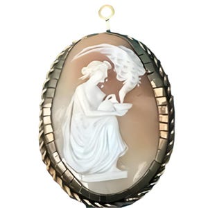 Può includere: Un ciondolo cammeo ovale con un rilievo bianco scolpito di una figura seduta che tiene una brocca e una ciotola su uno sfondo marrone chiaro. Il pezzo è racchiuso in una cornice di metallo color oro testurizzato con una piccola maglia circolare.