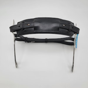 Peut inclure: Une têtière de bride pour cheval en cuir noir avec une partie supérieure rembourrée et des montants en métal argenté. Le cuir présente des coutures détaillées et des sangles réglables avec des boucles en métal, conçues pour l'équitation.
