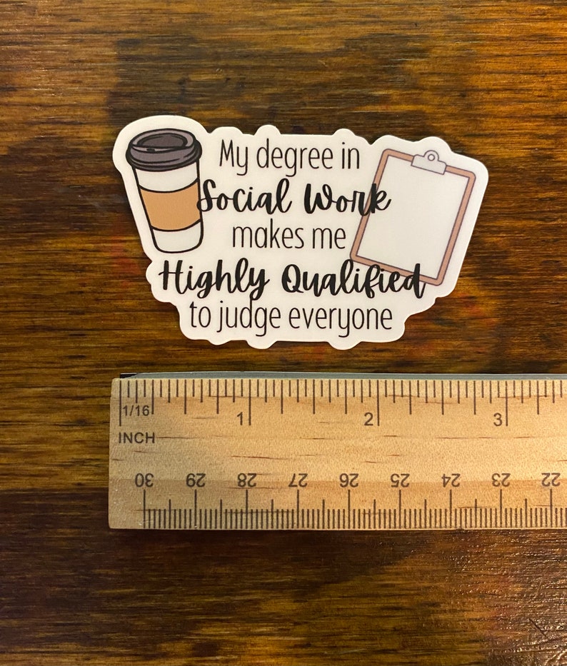 以下が含まれることがあります： コーヒーカップとクリップボードが描かれた白いステッカー。テキストは「ソーシャルワークの学位は、私を非常に有資格にし、すべての人を判断することができます。」