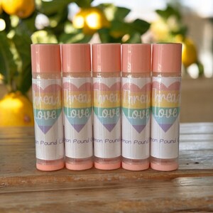 May include: Five pink lip balm tubes with a rainbow heart and the text "Thread Love" on the label. The text "Lemon Pound Cotton" is also on the label.