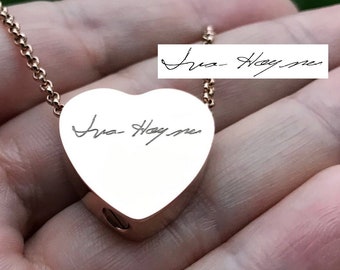 May include: A gold heart-shaped pendant necklace with a handwritten signature that reads "Iva Haymer" on the front.