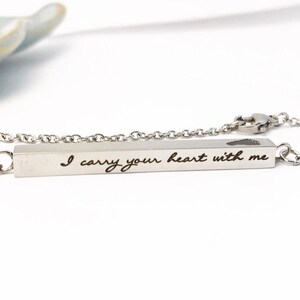 May include: Silver necklace with a bar pendant that reads "I carry your heart with me". The bar pendant has a small heart cutout.