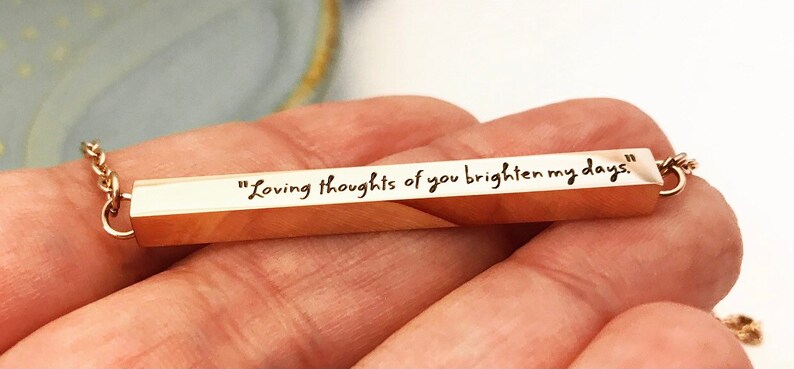 May include: Gold bar necklace with the inscription "Loving thoughts of you brighten my days."