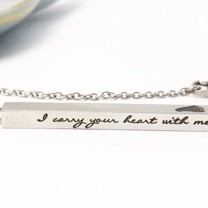 May include: A silver necklace with a bar pendant that reads "I carry your heart with me" and a small heart cutout.