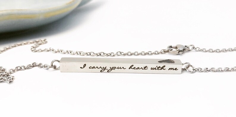May include: A silver necklace with a bar pendant that reads "I carry your heart with me" and a small heart cutout.
