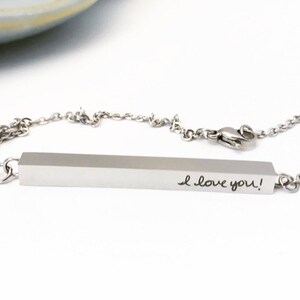 May include: A silver necklace with a bar pendant that says "I love you!" in handwritten script.