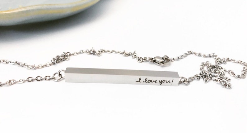 May include: A silver necklace with a bar pendant that says "I love you!" in handwritten script.