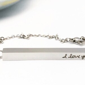 May include: A silver necklace with a bar pendant that says "I love you!" The bar pendant is attached to a silver chain.