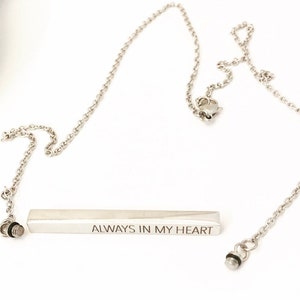 May include: Silver necklace with a bar pendant that reads "ALWAYS IN MY HEART".