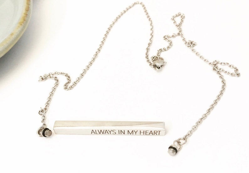 May include: Silver necklace with a bar pendant that reads "ALWAYS IN MY HEART".
