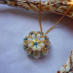 May include: A gold chain necklace with a white and blue beaded pendant featuring a crystal center.