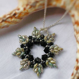 May include: A silver chain necklace with a black and green beaded pendant in the shape of a starburst.