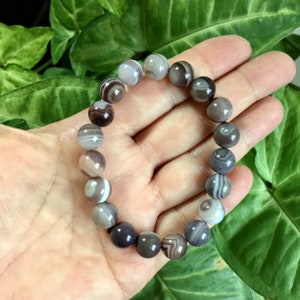 May include: A bracelet made of brown, white, and gray agate beads. The beads are round and have a natural, polished finish.