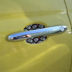 May include: A yellow car door with a silver door handle. The handle has a skull and crossbones design on the cover.