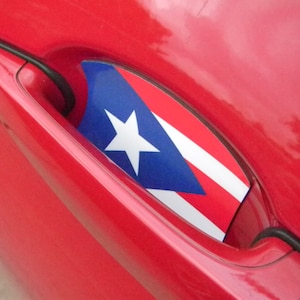 Puede incluir: Una puerta de coche roja con una pegatina de la bandera de Puerto Rico en la manija de la puerta.
