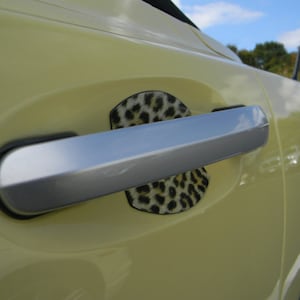 Peut inclure: Une portière de voiture jaune avec une poignée de porte argentée et un autocollant léopard sur la porte.