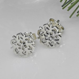 May include: A pair of silver snowflake stud earrings. The snowflakes are detailed and intricate.