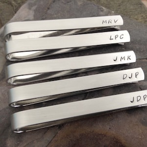 May include: Five silver tie bars with engraved initials. The initials are MRV, LPC, JMK, DJP, and JDP.