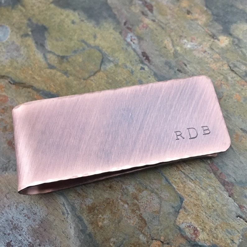 以下が含まれることがあります： 前面に「RDB」の刻印が施された、ブラシ仕上げの銅製のマネークリップです。