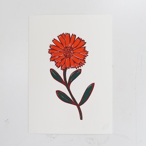 May include: A red and green linocut print of a single orange flower with a green stem and leaves.