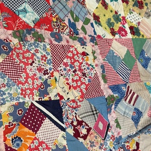 May include: A patchwork quilt constructed from various fabric squares featuring a diverse array of patterns including floral prints, gingham checks, polka dots, and geometric designs in colors such as red, blue, yellow, pink, and white.