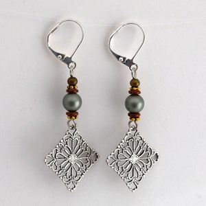 May include: Silver filigree earrings with a gray pearl and brown and gold beads.