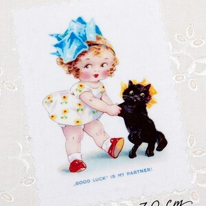 May include: A vintage-style illustration on a white fabric. It depicts a young girl in a floral dress and a large blue bow, holding hands with a black cat. The text reads "GOOD LUCK IS MY PARTNER!" The fabric measures approximately 4 x 2.75 inches.