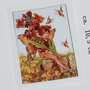 Op de afbeelding: Een postzegel met een fee met vlindervleugels, omringd door bloemen en vlinders. De postzegel is ongeveer 10,5 cm bij 7,5 cm, met een gezaagde rand. De fee draagt een rood-bruine outfit.