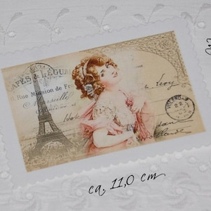 Könnte beinhalten: Eine Vintage-Postkarte mit einer Frau mit einer Blume im Haar, einem Blick auf den Eiffelturm und dem Text "Cafes & Legum Rue Mission de France" und "Leory". Die Postkarte misst etwa 8,0 cm x 11,0 cm.